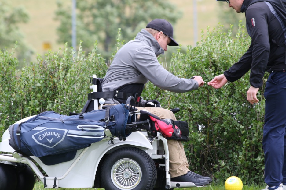Paragolfari ojentaa tiin toiselle henkilölle golfkentällä.