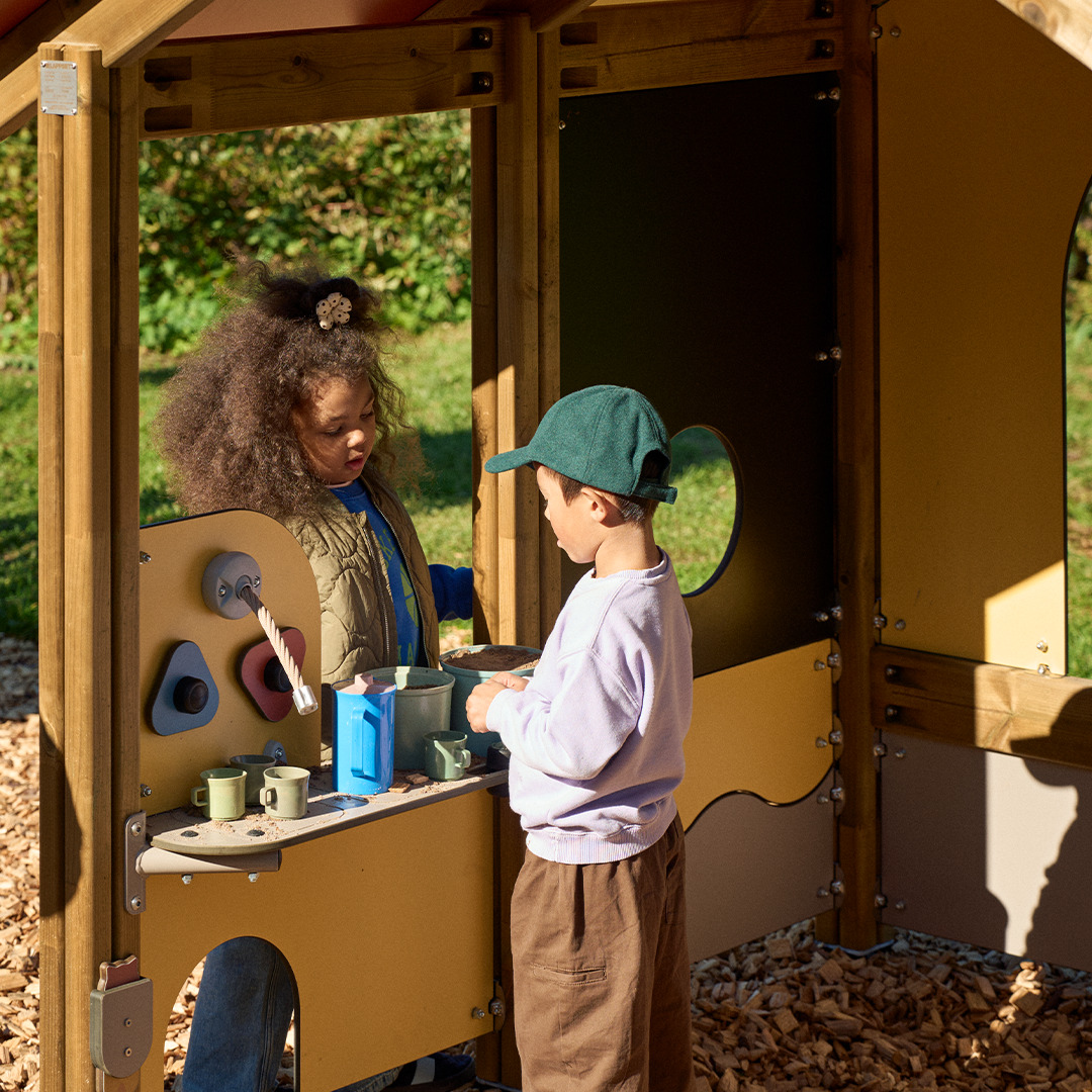 Poika ja tyttö leikkii pihalla leikkipuistossa.